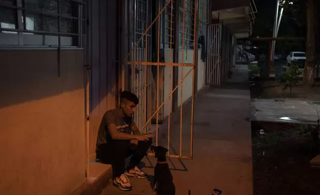 A student plays with a dog outside his dormitory at the Raúl Isidro Burgos Rural Normal School in Ayotzinapa, Guerrero state, Mexico, Sunday, Aug. 25, 2024. (AP Photo/Felix Marquez)