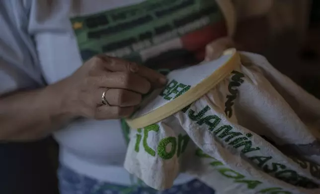 Cristina Bautista, whose son Benjamin Ascencio is one of 43 missing students from the Raúl Isidro Burgos Rural Normal School who went missing 10 years prior, embroiders her son's name at home in Tixtla, Guerrero state, Mexico, Friday, Aug. 23, 2024. (AP Photo/Felix Marquez)