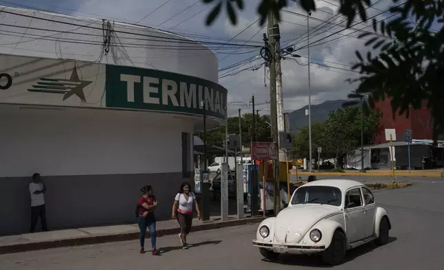 People walk outside the bus terminal in Iguala, Guerrero state, Mexico, Saturday, Sept. 7, 2024. Ten years ago, about 100 students from the Raúl Isidro Burgos Rural Normal School commandeered buses to drive themselves to a protest in the capital, but were attacked and 43 of them went missing. (AP Photo/Felix Marquez)