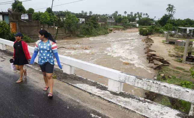 Women walk on a bridge in the aftermath of Hurricane John, in Acapulco, Mexico, Friday, Sept. 27, 2024. (AP Photo/Bernardino Hernandez)