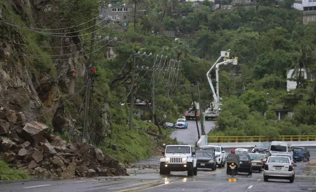 Residents drive past power lines damaged during the passing of Hurricane John, in Acapulco, Mexico, Friday, Sept. 27, 2024. (AP Photo/Bernardino Hernandez)