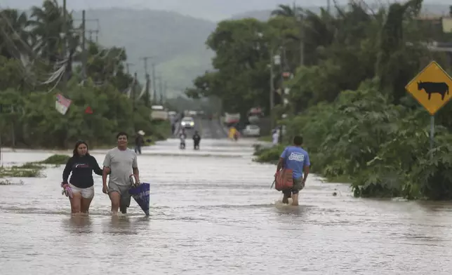 Residents wade through a street flooded by the passing of Hurricane John, in Acapulco, Mexico, Friday, Sept. 27, 2024. (AP Photo/Bernardino Hernandez)