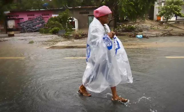 A person wearing plastic walks in the street after the passing of Hurricane John in Marquelia, Mexico, Tuesday, Sept. 24, 2024. (AP Photo/Luis Alberto Cruz)