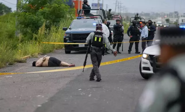 Law enforcement officials rope off an area where a body was found lying on the side of a road in Culiacan, Sinaloa state, Mexico, Saturday, Sept. 21, 2024. (AP Photo/Eduardo Verdugo)