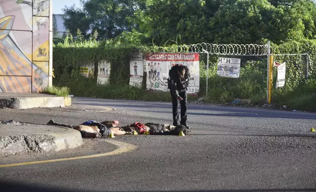 A police officer photographs a crime scene of bodies lying on the ground in Culiacan, Sinaloa state, Mexico, Wednesday, Sept. 18, 2024. (AP Photo)