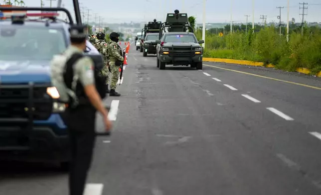 Soldiers traveling in armored vehicles patrol an area where a body was found lying on the side of a road, in Culiacan, Sinaloa state, Mexico, Saturday, Sept. 21, 2024. (AP Photo/Eduardo Verdugo)