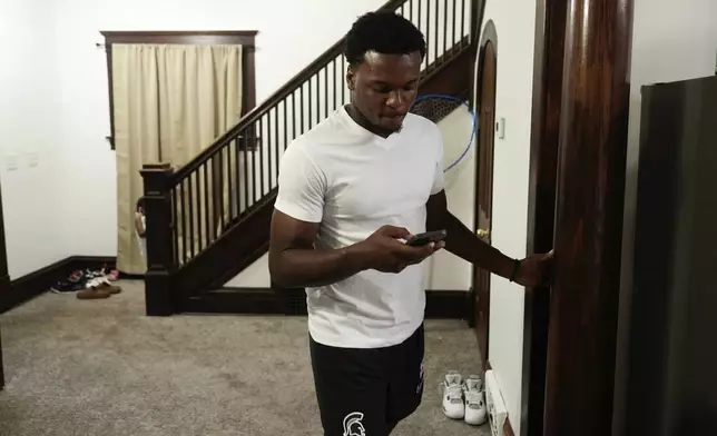 Armorion Smith, an NCAA football player at Michigan State, checks his phone at home in Lansing, Mich., Tuesday, Sept. 3, 2024. (AP Photo/Paul Sancya)