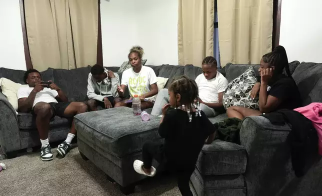 Armorion Smith, left, reviews game video on his phone as he sits with his siblings, from left, Arial, Aleion, Amaira, Armond, and Avaugn, at home in Lansing, Mich., Tuesday, Sept. 3, 2024. (AP Photo/Paul Sancya)