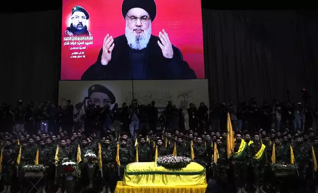 FILE - Hezbollah fighters stand behind the coffin of their top commander Fouad Shukur, who was killed by an Israeli airstrike on July 30, as Hezbollah leader Sayyed Hassan Nasrallah speaks through a screen during Shukur's funeral in a southern suburb of Beirut, Lebanon, Aug. 1, 2024. (AP Photo/Hussein Malla, File)