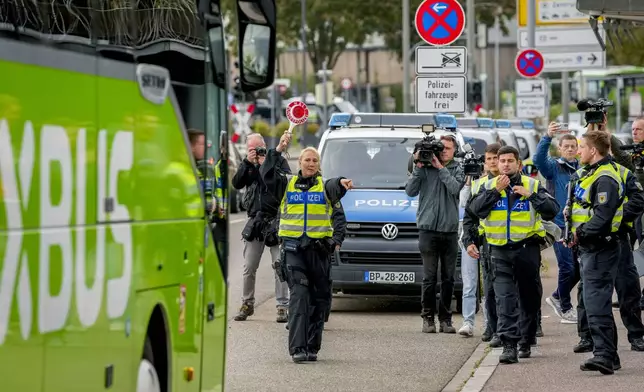 A German police officer stops a bus at the border between Germany and France, in Kehl, Germany, Monday, Sept. 16, 2024, as Germany begins carrying out checks at all its land borders. (AP Photo/Michael Probst)