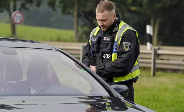 A German police officer checks the details of a French car near the border to Belgium in Aachen, Germany, Monday, Sept. 16, 2024, as Germany begins carrying out checks at all its land borders. (AP Photo/Martin Meissner)