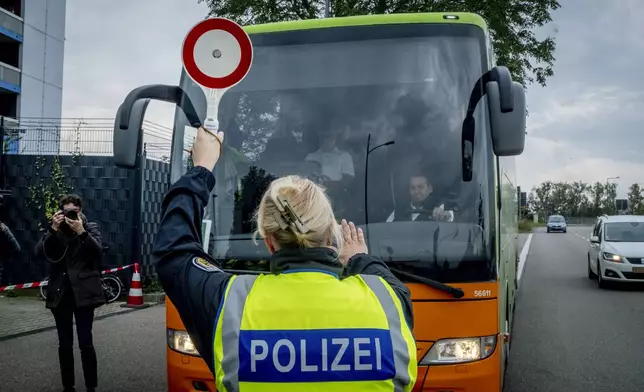 A German police officer stops a bus at the border between Germany and France in Kehl, Germany, Monday, Sept. 16, 2024, as Germany begins carrying out checks at all its land borders. (AP Photo/Michael Probst)