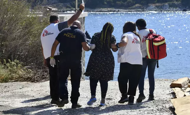 Members of Doctors Without Borders and a coast guard officer help a pregnant woman who survived after a boat carrying migrants ran into trouble off the coast of the eastern Aegean Sea island of Samos, Greece, on Monday, Sept. 23, 2024. (AP Photo/Michael Svarnias)