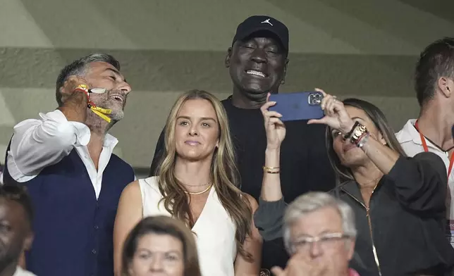 American former professional basketball player Michael Jordan, center, gestures as he poses for a selfie while attend the start of the Champions League opening phase soccer match between Monaco and Barcelona at the Louis II stadium, in Monaco, Monaco, Thursday, Sept. 19, 2024. (AP Photo/Laurent Cipriani)