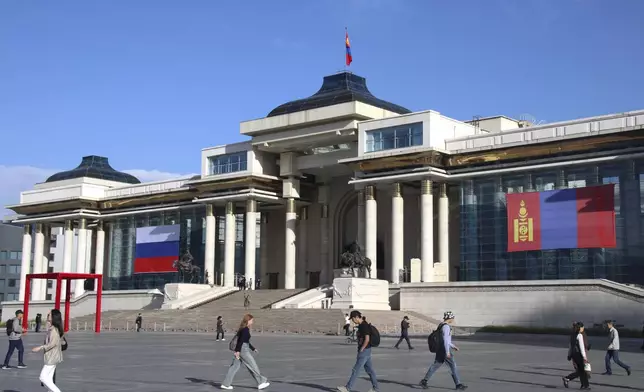 People walk in Sukhbaatar Square, decorated with the national flags of Mongolia and Russia, to welcome the visit of Russian President Vladimir Putin in Ulaanbaatar, Mongolia, Tuesday, Sept. 3, 2024. (AP Photo/Ganbat Namjilsangarav)