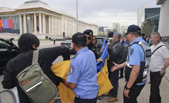 Police and security officers prevent members of the "No War" group from holding up a Ukrainian flag during the visit of Russian President Vladimir Putin in Ulaanbaatar, Mongolia, Tuesday, Sept. 3, 2024. (AP Photo/Ganbat Namjilsangarav)