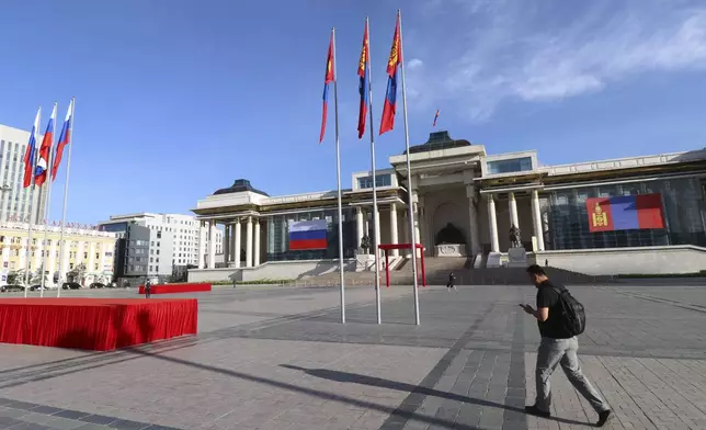 A man walks past Sukhbaatar Square, decorated with the national flags of Mongolia and Russia, to welcome the visit of Russian President Vladimir Putin in Ulaanbaatar, Mongolia, Tuesday, Sept. 3, 2024. (AP Photo/Ganbat Namjilsangarav)