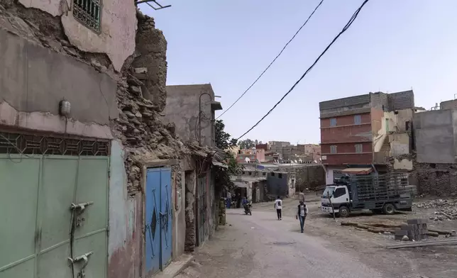 People walk past buildings which were affected by the 2023 earthquake, in the town of Amizmiz, outside Marrakech, Morocco, Wednesday, Sept. 4, 2024. (AP Photo/Mosa'ab Elshamy)