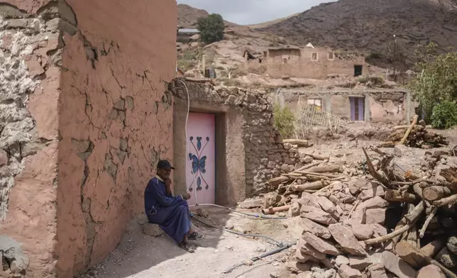 A man sits outside a home which was damaged in a 2023 earhquake, Thursday, Sept. 5, 2024, in the Atlas village of Tinmel, outside of Marrakech, Morocco. (AP Photo/Mosa'ab Elshamy)