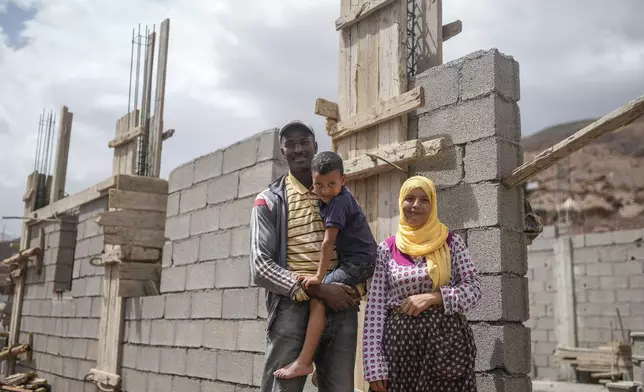 Redwan Ait Salah stands with his son, Tarik, and wife, Khadija Diwan, outside a house they are building, after their home was destroyed in a 2023 earthquake, in the Atlas mountain village of Tinmel, outside of Marrakech, Morocco, Thursday, Sept. 5, 2024. (AP Photo/Mosa'ab Elshamy)