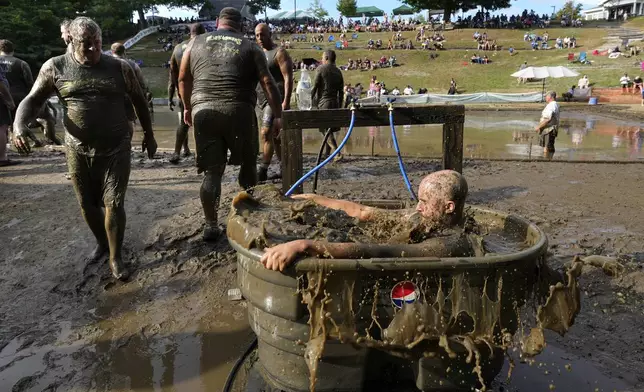 A Muckaneer's player dunks himself in a tub to clean off after a football game at the 2024 Mud Bowl Sunday, Sept. 8, 2024, in North Conway, N.H. (AP Photo/Robert F. Bukaty)