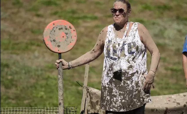 Mud-splattered sideline official Kellie Gramstorff holds a first down marker during a football game at the Mud Bowl in North Conway, N.H., Saturday, Sept. 7, 3024. (AP Photo/Robert F. Bukaty)