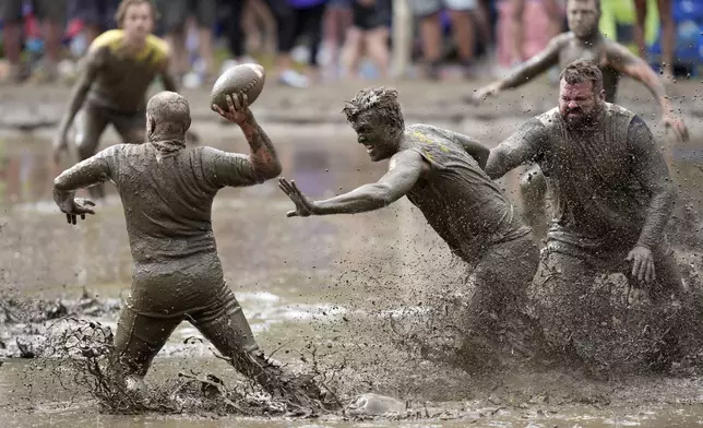 The Mudshark's Jevin Smith, center, gets around Muddas' blocker Kurt Mailloux to put pressure on quarterback Jay Holder in a football game at the 2024 Mud Bowl Sunday, Sept. 8, 2024, in North Conway, N.H. (AP Photo/Robert F. Bukaty)