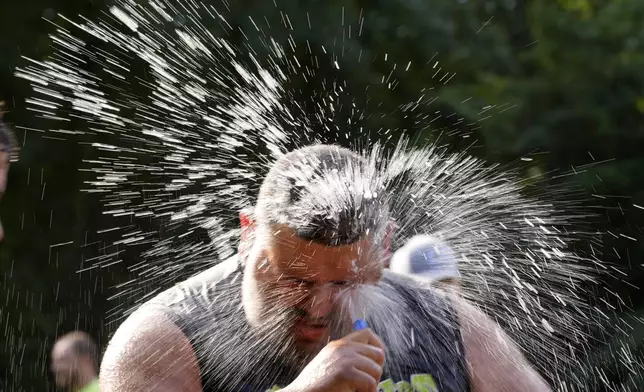 Jacob "Moose" Colon, of Westfield, Mass., of the Muckaneers, hoses off after a football game at the Mud Bowl in North Conway, N.H., Saturday, Sept. 7, 3024. (AP Photo/Robert F. Bukaty)