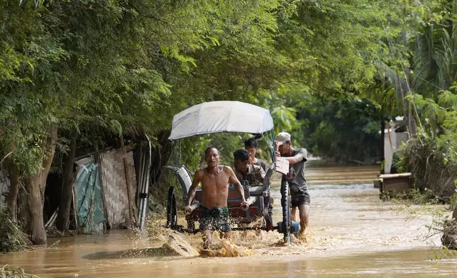 Local residents carrying food on their cart wade through a flooded road in Naypyitaw, Myanmar, Saturday, Sept. 14, 2024. (AP Photo/Aung Shine Oo)