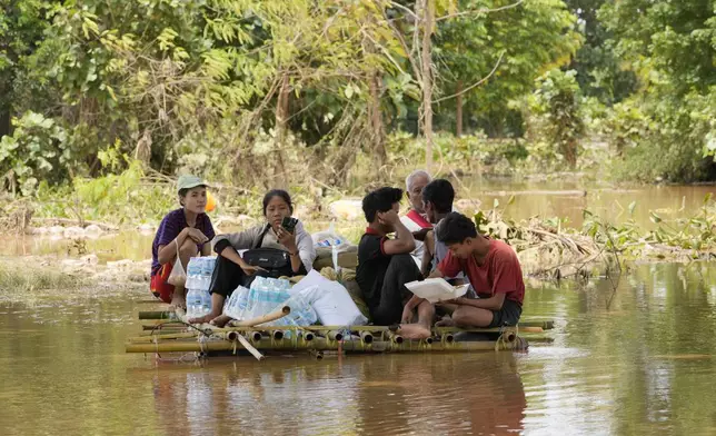 Flood victims rest on a bamboo raft with their food on a flooded road in Naypyitaw, Myanmar, Saturday, Sept. 14, 2024. (AP Photo/Aung Shine Oo)