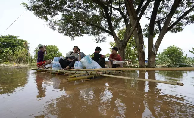 Flood victims rest on a bamboo raft with their food on a flooded road in Naypyitaw, Myanmar, Saturday, Sept. 14, 2024. (AP Photo/Aung Shine Oo)