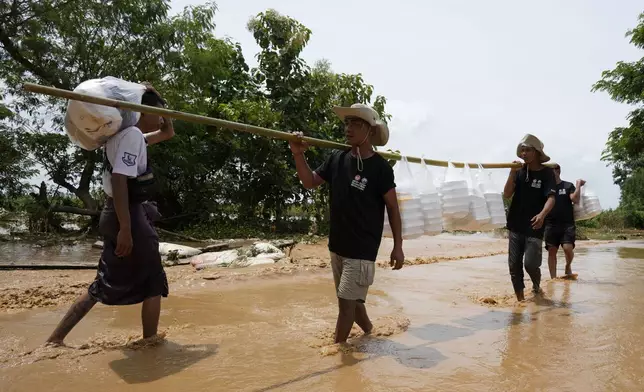 Local residents carrying foods wade through a flooded road in Naypyitaw, Myanmar, Saturday, Sept. 14, 2024. (AP Photo/Aung Shine Oo)