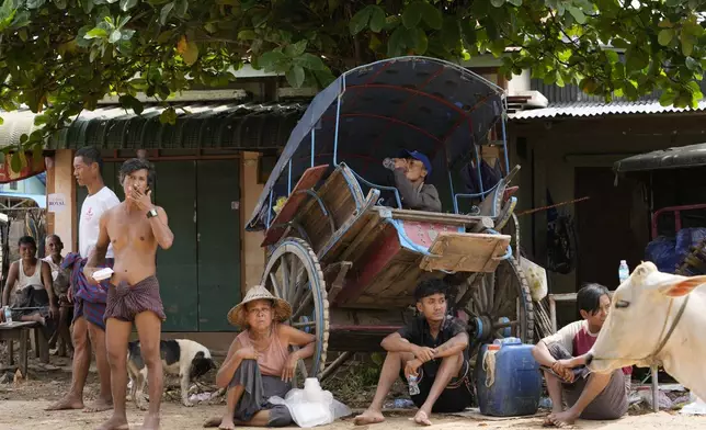 Local residents rest near a flooded road in Naypyitaw, Myanmar, Saturday, Sept. 14, 2024. (AP Photo/Aung Shine Oo)