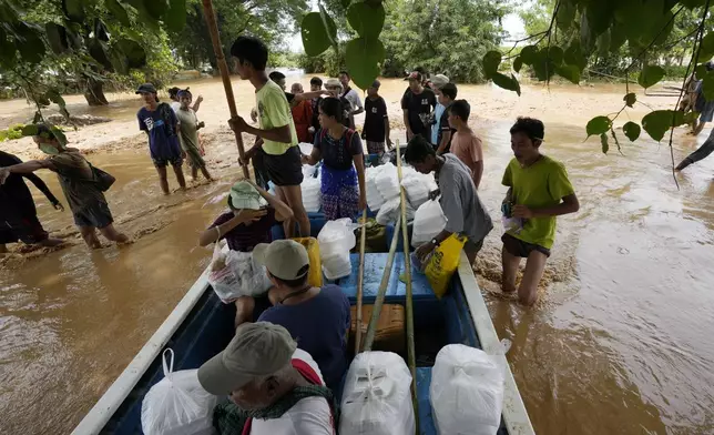 Volunteers gather to distribute foods to flood victims on a flooded road in Naypyitaw, Myanmar, Saturday, Sept. 14, 2024. (AP Photo/Aung Shine Oo)