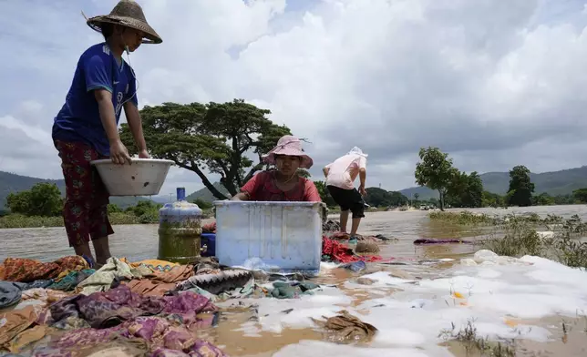 Local residents wash clothes along a flooded road in Naypyitaw, Myanmar, Sunday, Sept. 15, 2024. (AP Photo/Aung Shine Oo)