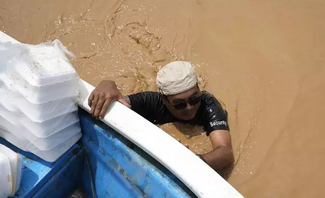 Local residents carrying food wade through a flooded road in Naypyitaw, Myanmar, Saturday, Sept. 14, 2024. (AP Photo/Aung Shine Oo)