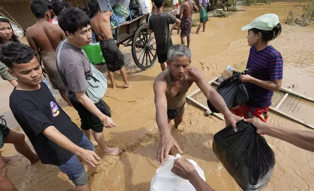 Local residents carrying food wade through a flooded road in Naypyitaw, Myanmar, Saturday, Sept. 14, 2024. (AP Photo/Aung Shine Oo)