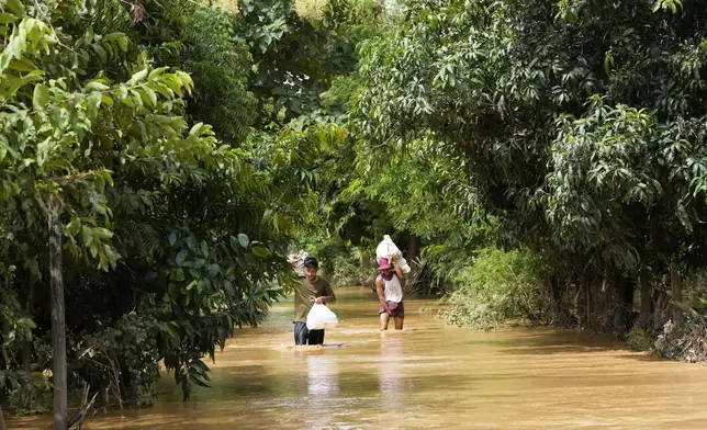 Local residents carrying food wade through a flooded road in Naypyitaw, Myanmar, Saturday, Sept. 14, 2024. (AP Photo/Aung Shine Oo)