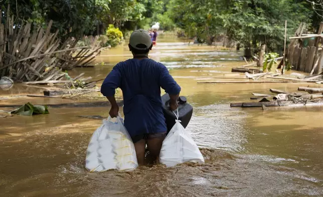 Local residents carrying food wade through a flooded road in Naypyitaw, Myanmar, Saturday, Sept. 14, 2024. (AP Photo/Aung Shine Oo)