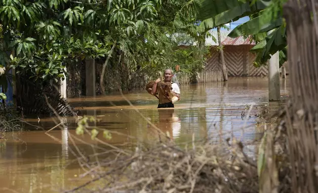 A man carrying a dog wades through a flooded road in Naypyitaw, Myanmar, Saturday, Sept. 14, 2024. (AP Photo/Aung Shine Oo)