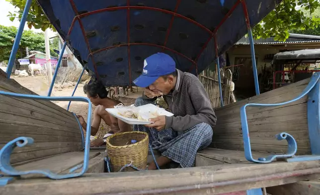 Local resident eat meal on a cart near a flooded road in Naypyitaw, Myanmar, Saturday, Sept. 14, 2024. (AP Photo/Aung Shine Oo)