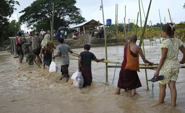 Local residents wade through flooded water at a broken bridge, in Naypyitaw, Myanmar, Tuesday, Sept. 17, 2024. (AP Photo/Aung Shine Oo)