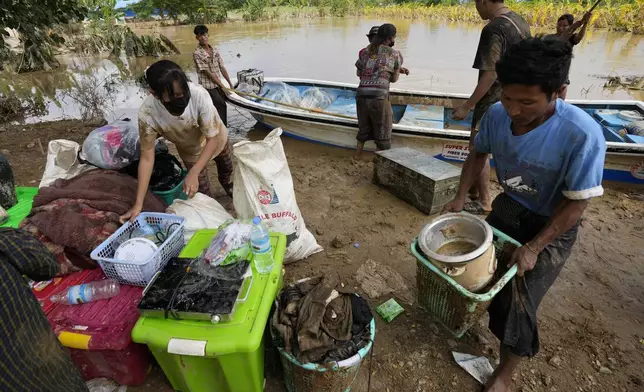 Local residents carry their belongings along a flooded road, in Naypyitaw, Myanmar, Tuesday, Sept. 17, 2024. (AP Photo/Aung Shine Oo)