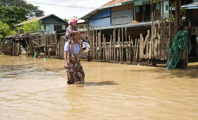 A women and child wade through a flooded road, in Naypyitaw, Myanmar, Myanmar, Tuesday, Sept. 17, 2024. (AP Photo/Aung Shine Oo)