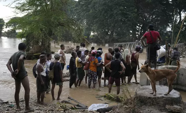 Local residents wade through flooded water at a broken bridge, in Naypyitaw, Myanmar, Tuesday, Sept. 17, 2024. (AP Photo/Aung Shine Oo)