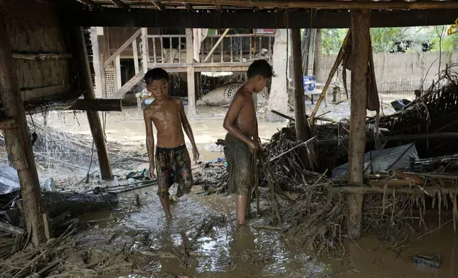 Boys try to clean up the debris from a flooding at home in Naypyitaw, Myanmar, Wednesday, Sept. 18, 2024. (AP Photo/Aung Shine Oo)