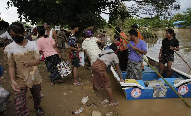 Local residents carry their belongings along a flooded road, in Naypyitaw, Myanmar, Tuesday, Sept. 17, 2024. (AP Photo/Aung Shine Oo)