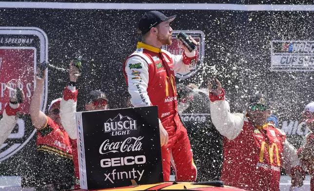 Tyler Reddick stands on his car after winning a NASCAR Cup Series auto race at Michigan International Speedway, Monday, Aug. 19, 2024, in Brooklyn, Mich. (AP Photo/Carlos Osorio)