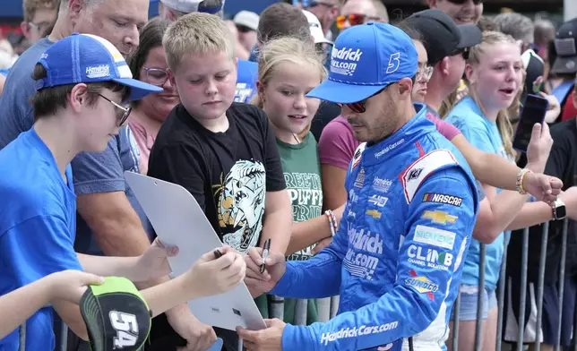 Kyle Larson signs autographs before driver introductions of a NASCAR Cup Series auto race at Michigan International Speedway, Sunday, Aug. 18, 2024, in Brooklyn, Mich. (AP Photo/Carlos Osorio)