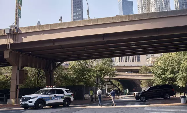 A police officer sits at his car as he guards outside One Police Plaza NYPD Headquarters on Friday, Sept. 13, 2024, in New York. (AP Photo/Andres Kudacki)